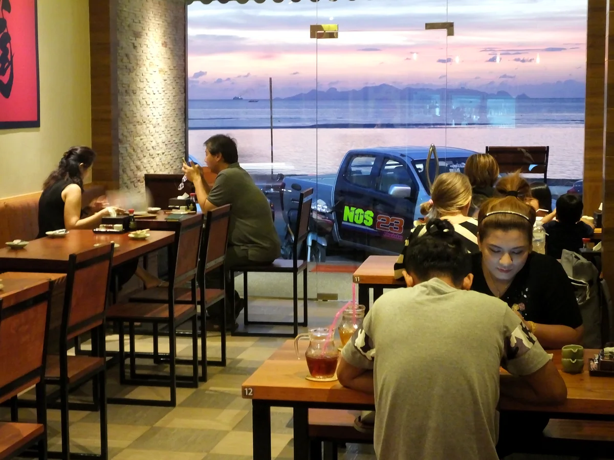 Guests dining inside KOBORI with the sea visible beyond the restaurant